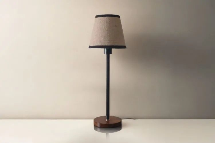 En enkel bordslampa med varmt sken mot en lugn, neutral vägg